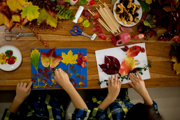 istock Children, applying leaves using glue, scissors, and paint, while doing arts and crafts in school 1061676872