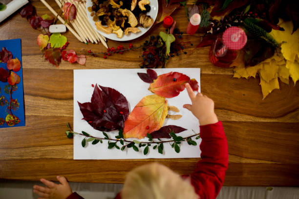 istock Children, applying leaves using glue, scissors, and paint, while doing arts and crafts in school 1061676978