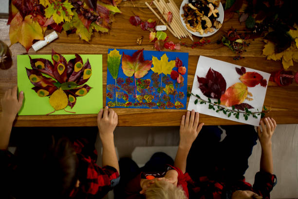 istock Children, applying leaves using glue, scissors, and paint, while doing arts and crafts in school 1061677070