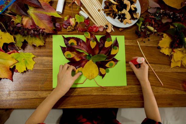 istock Children, applying leaves using glue, scissors, and paint, while doing arts and crafts in school 1061677182