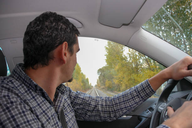 istock car and young driver passing by train tracks and safety important 1061685614