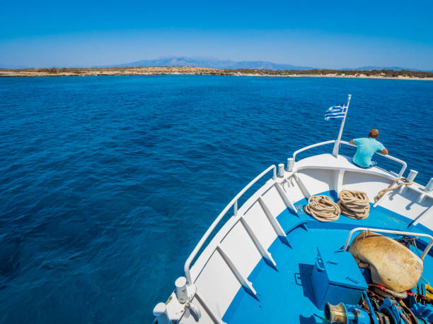 griechische flagge winken am bug eines bootes in richtung der insel chrissi oder in der karibik in griechenland segeln - chrissy stock-fotos und bilder