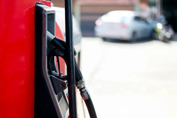 closeup of red fuel pumps at a gas station with soft-focus and over light in the background