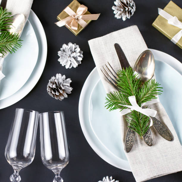 istock Christmas table setting with plates, silverware, gift box and decorations in black and gold colors 1061697460