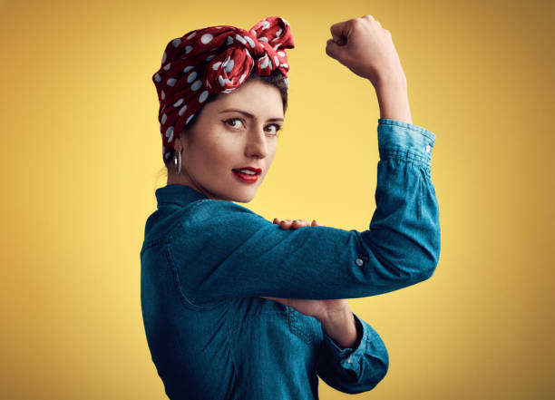 I can do it all Studio portrait of an attractive young woman flexing her bicep while standing against a yellow background womens rights stock pictures, royalty-free photos & images