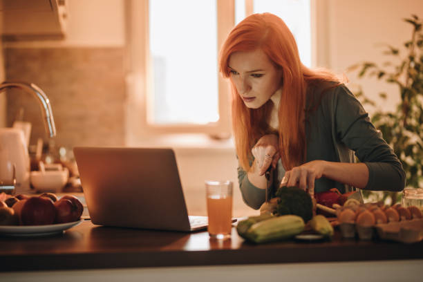 istock Redhead woman reading recipes on the Internet while cutting salad for lunch. 1061710772