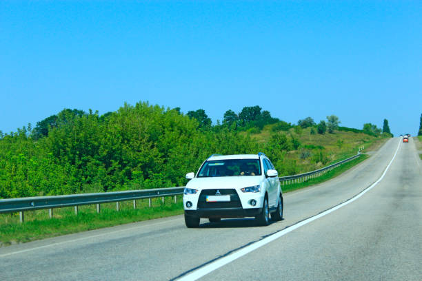 mitsubishi outlander bianca che va su strada asfaltata. concetto di viaggio - 11091 foto e immagini stock