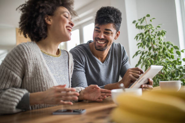 istock Young black couple laughing while surfing the net on touchpad. 1061714052