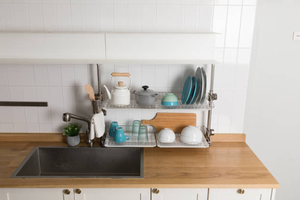 istock Clean dishes drying on metal dish rack on light background. Kitchen utensils and dishware on wooden shelf. Kitchen interior background.Text space. 1061716026