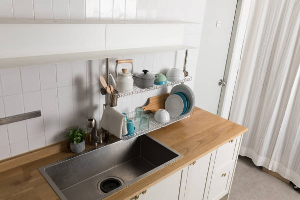 istock Clean dishes drying on metal dish rack on light background. Kitchen utensils and dishware on wooden shelf. Kitchen interior background.Text space. 1061716160