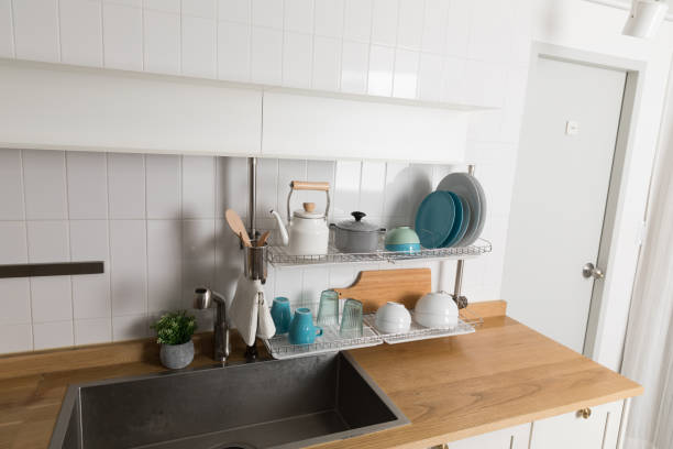 istock Clean dishes drying on metal dish rack on light background. Kitchen utensils and dishware on wooden shelf. Kitchen interior background.Text space. 1061716254