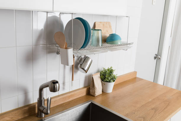 istock Clean dishes drying on metal dish rack on light background. Kitchen utensils and dishware on wooden shelf. Kitchen interior background.Text space. 1061716330