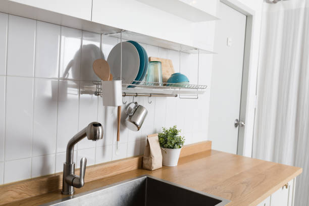 istock Clean dishes drying on metal dish rack on light background. Kitchen utensils and dishware on wooden shelf. Kitchen interior background.Text space. 1061716332