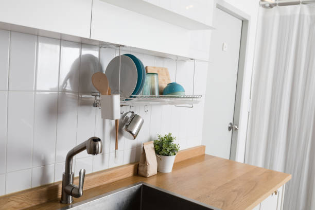 istock Clean dishes drying on metal dish rack on light background. Kitchen utensils and dishware on wooden shelf. Kitchen interior background.Text space. 1061716344