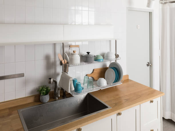 istock Clean dishes drying on metal dish rack on light background. Kitchen utensils and dishware on wooden shelf. Kitchen interior background.Text space. 1061716370