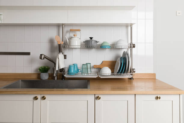 istock Clean dishes drying on metal dish rack on light background. Kitchen utensils and dishware on wooden shelf. Kitchen interior background.Text space. 1061716592