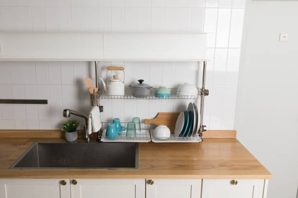 istock Clean dishes drying on metal dish rack on light background. Kitchen utensils and dishware on wooden shelf. Kitchen interior background.Text space. 1061716606