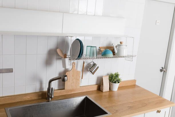 istock Clean dishes drying on metal dish rack on light background. Kitchen utensils and dishware on wooden shelf. Kitchen interior background.Text space. 1061716622