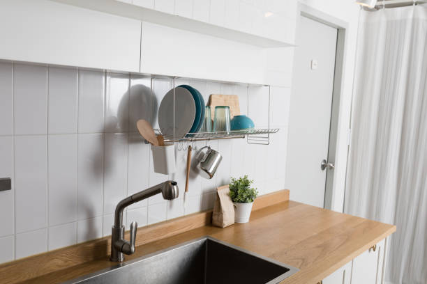 istock Clean dishes drying on metal dish rack on light background. Kitchen utensils and dishware on wooden shelf. Kitchen interior background.Text space. 1061716914