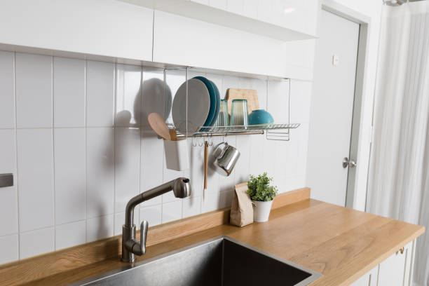 istock Clean dishes drying on metal dish rack on light background. Kitchen utensils and dishware on wooden shelf. Kitchen interior background.Text space. 1061717082