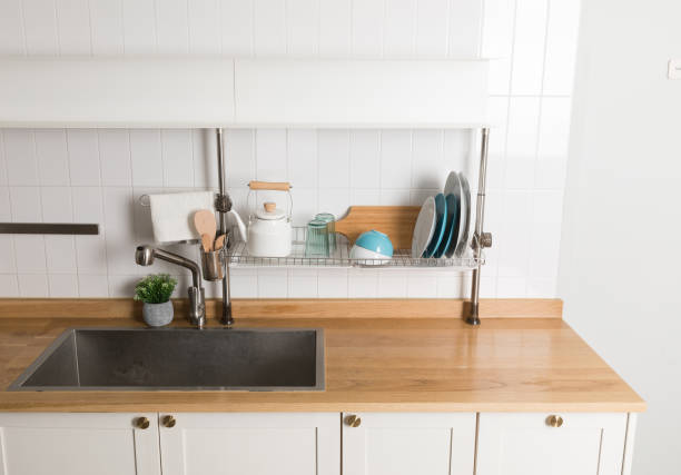 istock Clean dishes drying on metal dish rack on light background. Kitchen utensils and dishware on wooden shelf. Kitchen interior background.Text space. 1061717140