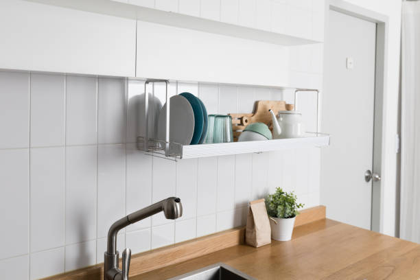 istock Clean dishes drying on metal dish rack on light background. Kitchen utensils and dishware on wooden shelf. Kitchen interior background.Text space. 1061717546