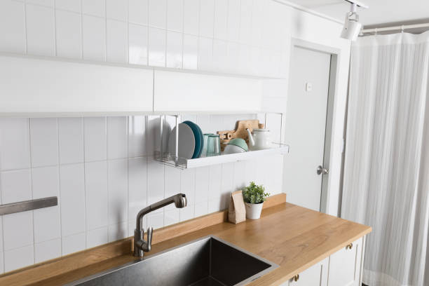 istock Clean dishes drying on metal dish rack on light background. Kitchen utensils and dishware on wooden shelf. Kitchen interior background.Text space. 1061717598