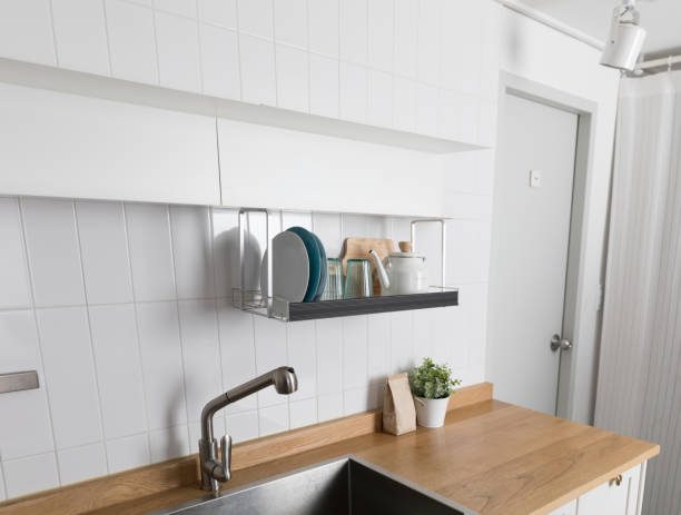 istock Clean dishes drying on metal dish rack on light background. Kitchen utensils and dishware on wooden shelf. Kitchen interior background.Text space. 1061718716
