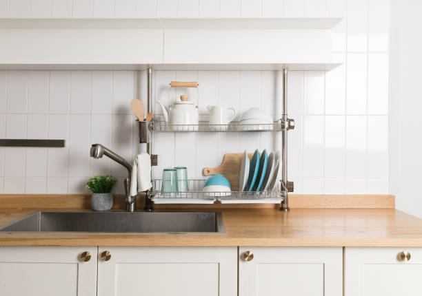 istock Clean dishes drying on metal dish rack on light background. Kitchen utensils and dishware on wooden shelf. Kitchen interior background.Text space. 1061719732
