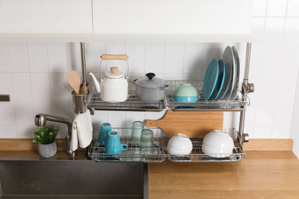 istock Clean dishes drying on metal dish rack on light background. Kitchen utensils and dishware on wooden shelf. Kitchen interior background.Text space. 1061720368