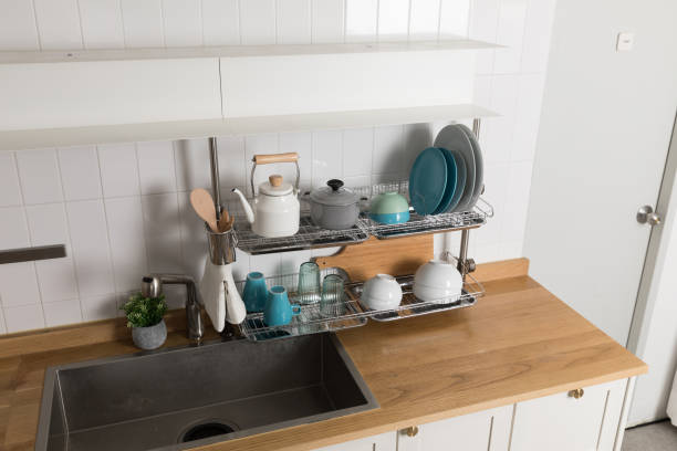 istock Clean dishes drying on metal dish rack on light background. Kitchen utensils and dishware on wooden shelf. Kitchen interior background.Text space. 1061720376