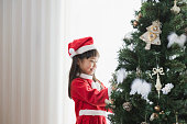 クリスマス ツリーを飾るサンタ クロースの衣装を着ている少女