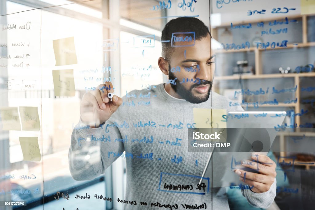 Plan to win every single day Shot of a young businessman using a digital tablet while having a brainstorming session in a modern office Glass - Material Stock Photo