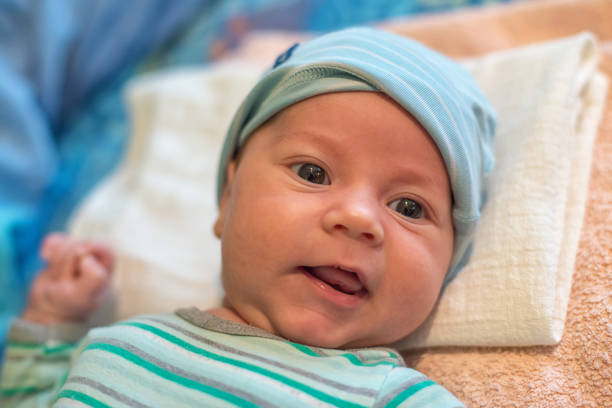 istock The newborn (2 months baby) with a hat  is lying on the bed and laughing 1061738166