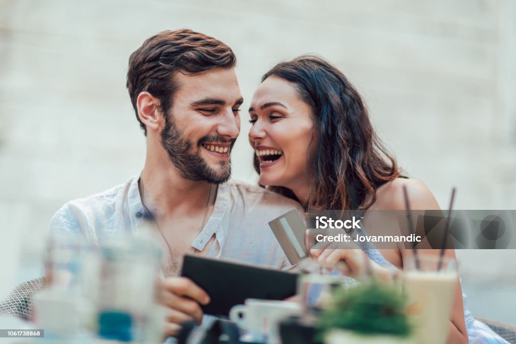 Beautiful couple having coffee on a date, using digital tablet and credit card for online shopping Credit Card Stock Photo