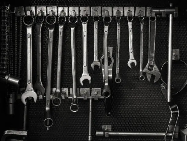 Black and white photo of old multiple wrenches size hanging on tool board in auto car service and maintenance station workshop, Monochrome