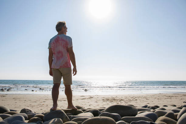 istock Man stands on boulders at empty beach 1061741822