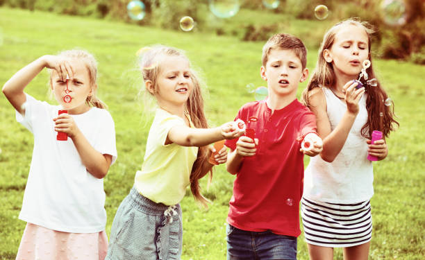istock Four  kids sitting together and blowing soap bubbles 1061742280