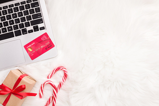 Shopping online with laptop and credit card on white fur background, copy space