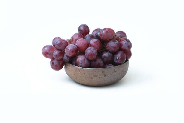 Red grapes on the ceramic bowl isolated on white