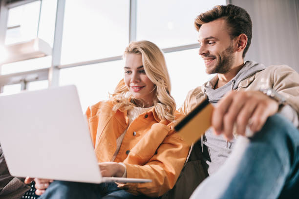 istock smiling young couple using laptop while waiting in airport, low angle view 1061750326