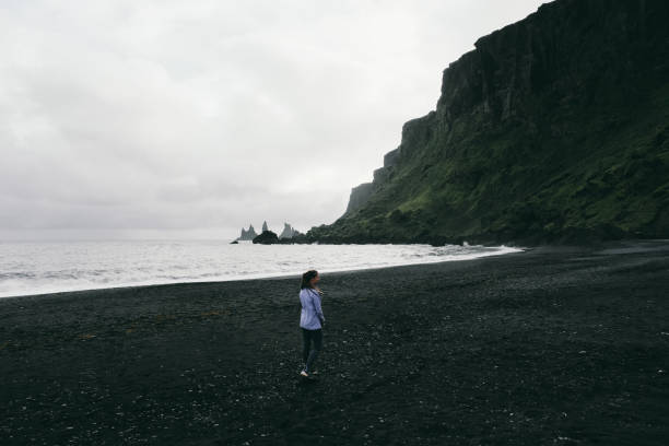 istock Woman walking at black sand beach in Vik in Iceland 1061751978