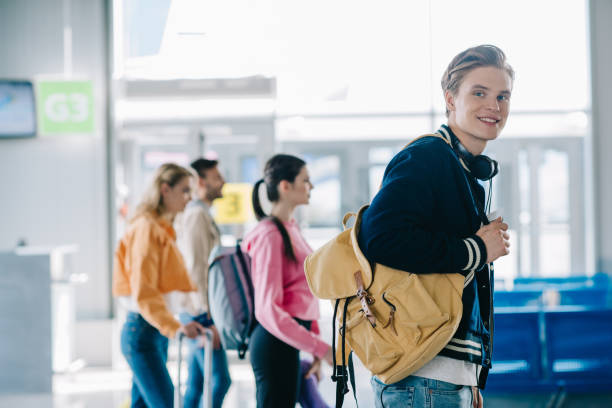 istock handsome young man with backpack smiling at camera while traveling with friends 1061757558