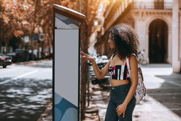 affascinante ragazza riccia paga il parchimetro all'aperto - biglietto di parcheggio foto e immagini stock