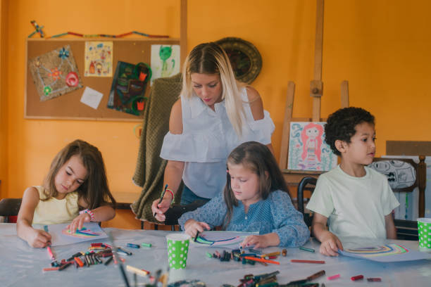 istock Teacher standing behind children painting 1061766504