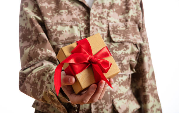 istock Young soldier holding a christmas gift standing on white background 1061791410