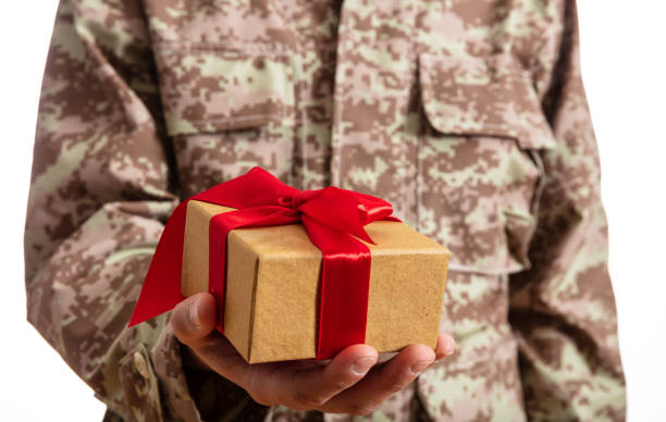 istock Young soldier holding a christmas gift standing on white background 1061791412