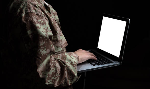 istock Young soldier working with a laptop computer with blank screen on black background 1061791552