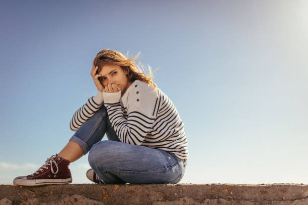 istock Woman sitting on a sea wall looking away 1061797126