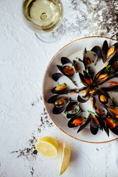 istock Boiled mussels and white wine on white stone table. 1061815284